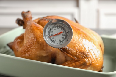 Photo of Roasted turkey with meat thermometer in baking dish