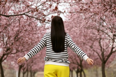 Young woman in park with blooming trees. Spring look