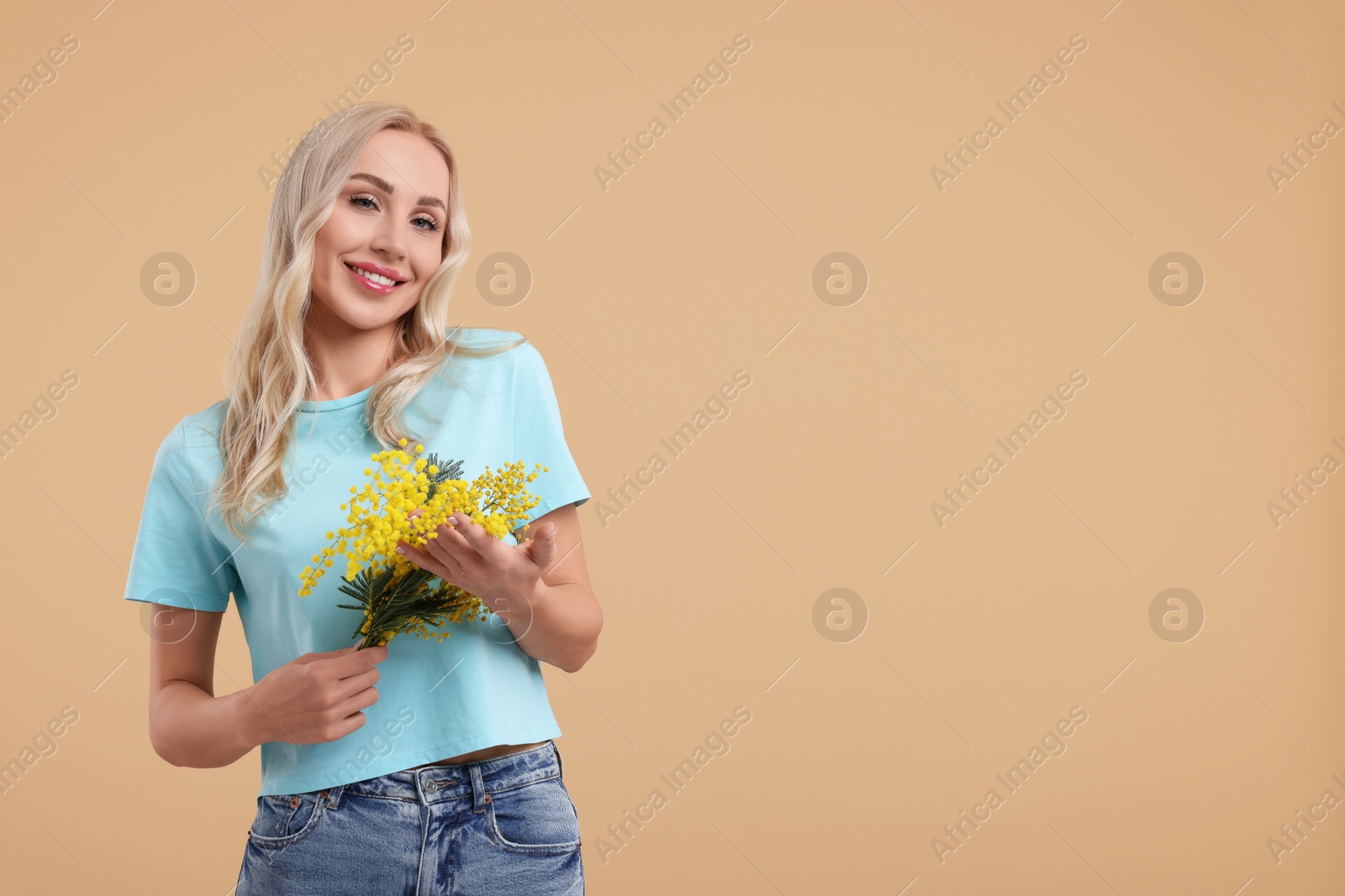 Photo of Happy young woman with beautiful bouquet on beige background. Space for text