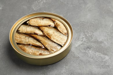 Photo of Sprats in tin can on grey textured table. Space for text