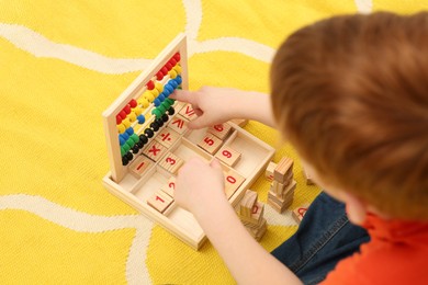 Photo of Child playing with math game kit on floor, above view. Learning mathematics with fun