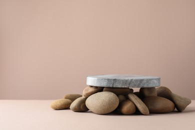 Photo of Presentation for product. Stone podium and pebbles on beige background. Space for text