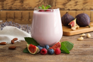 Photo of Delicious fig smoothie in glass on wooden table