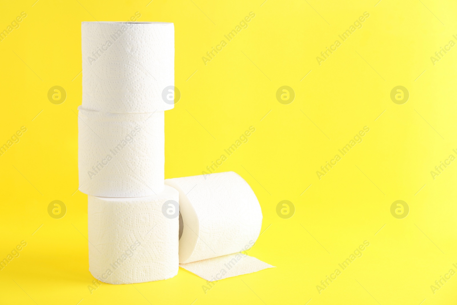 Photo of Many soft toilet paper rolls on yellow background. Space for text