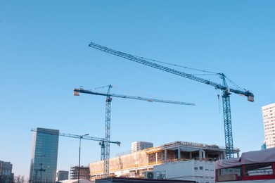 Construction cranes and unfinished building on sunny day