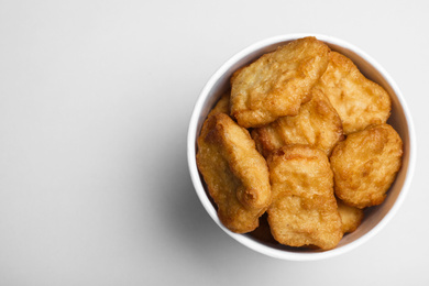 Photo of Bucket with delicious chicken nuggets on light background, top view. Space for text
