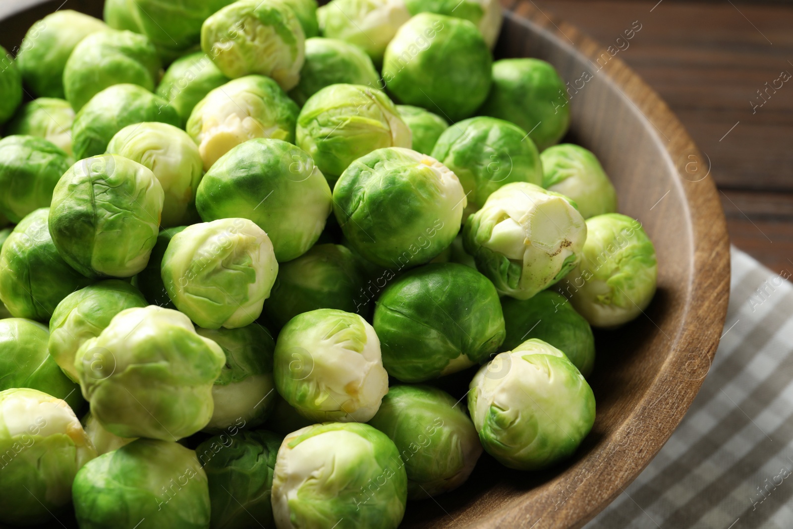 Photo of Fresh Brussels sprouts in bowl on table, closeup