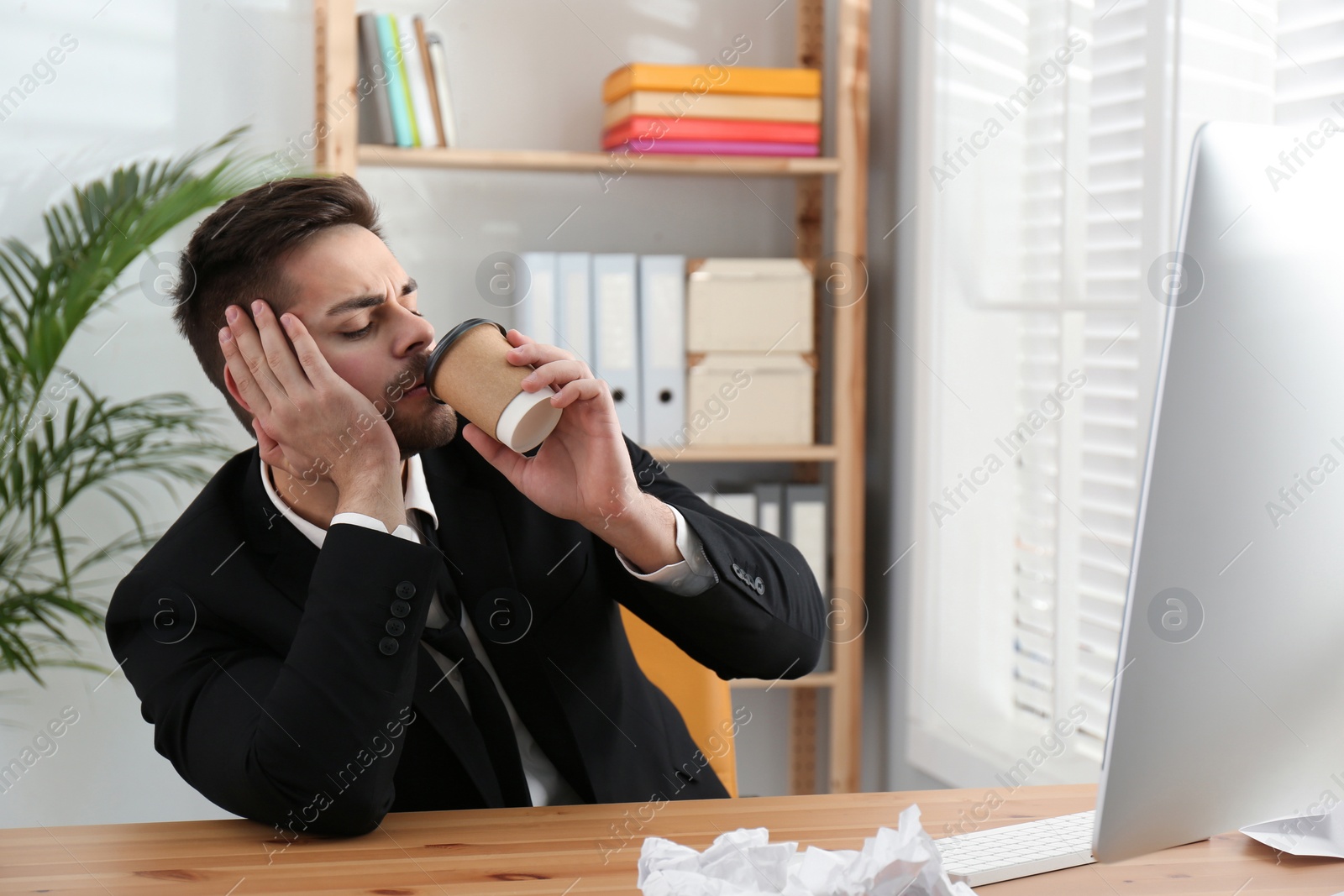 Photo of Lazy employee drinking coffee at table in office