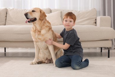 Photo of Cute child with his Labrador Retriever on floor at home. Adorable pet