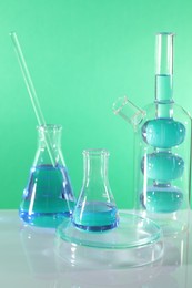 Photo of Laboratory analysis. Different glassware on table against green background