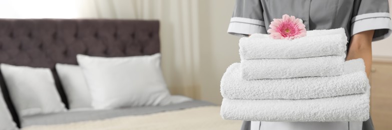 Image of Chambermaid with stack of fresh towels in hotel room, closeup view with space for text. Banner design