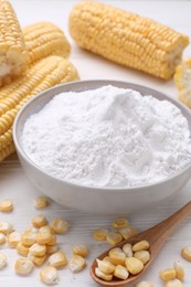 Photo of Bowl of corn starch, ripe cobs and kernels on white wooden table