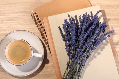 Photo of Bouquet of beautiful preserved lavender flowers, notebooks and cup of coffee on wooden table, flat lay