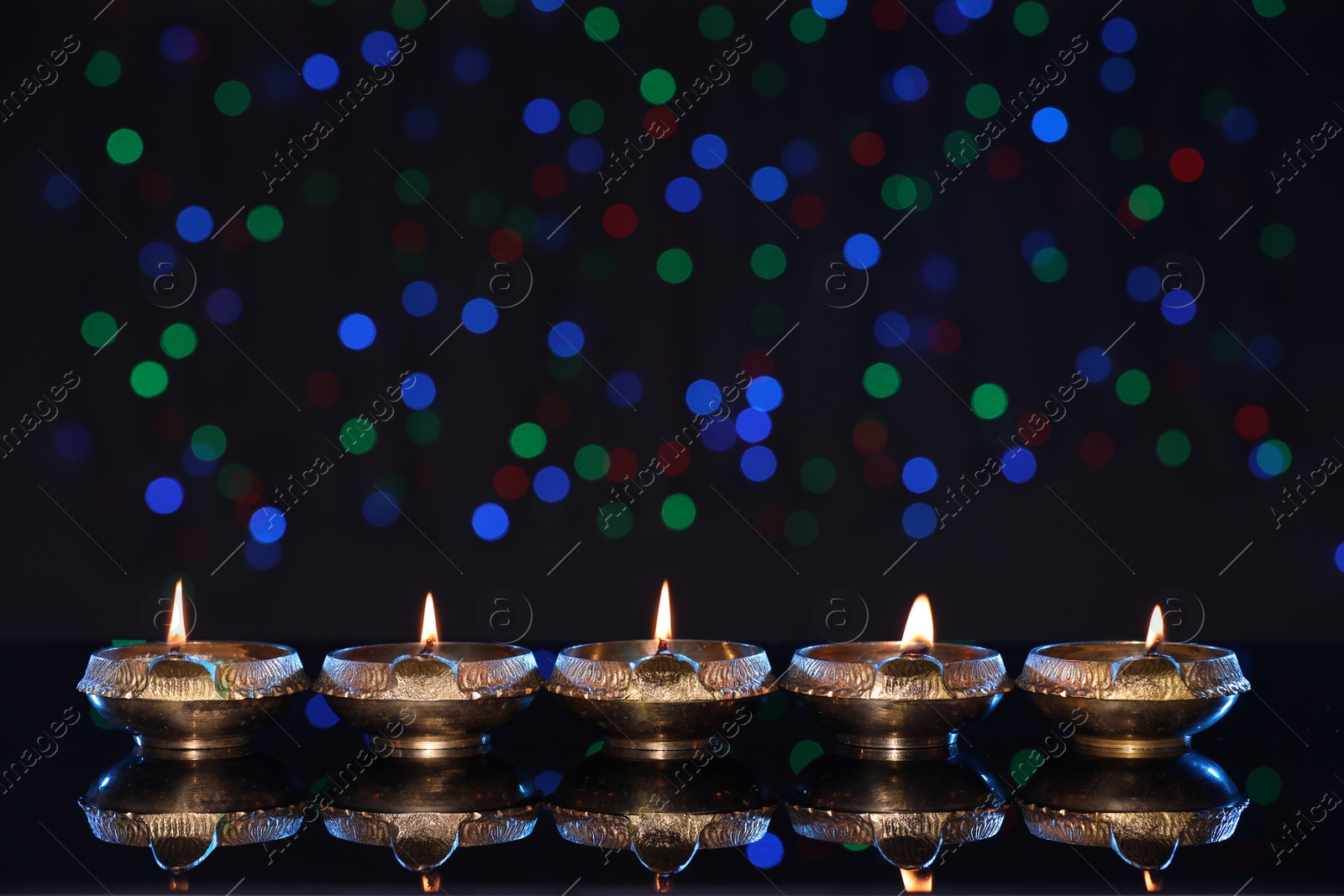 Photo of Many lit diyas on dark background with blurred lights, space for text. Diwali lamps