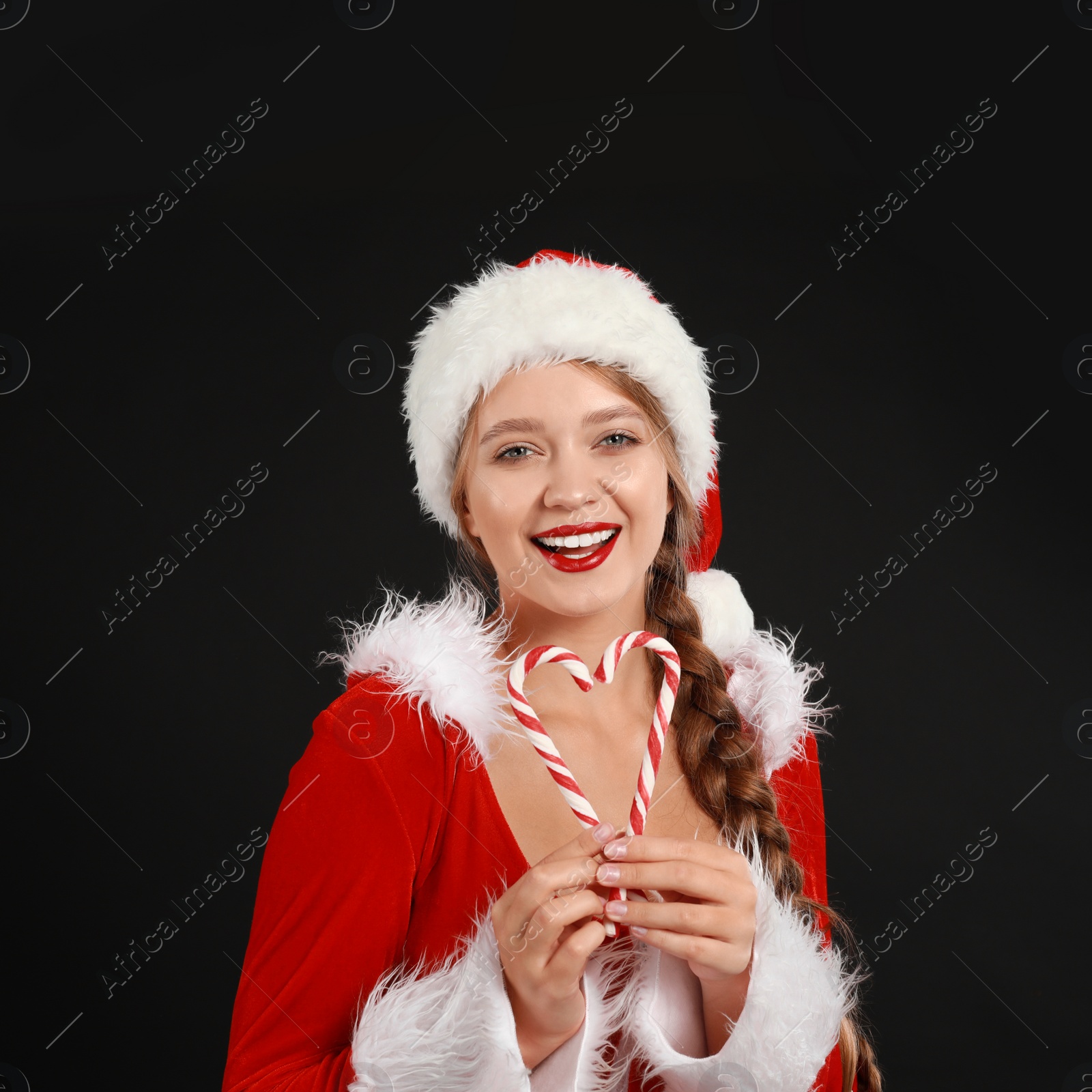 Photo of Beautiful Santa girl with candy canes on black background. Christmas eve