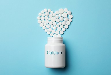 Calcium supplement. Bottles with pills on turquoise background, flat lay