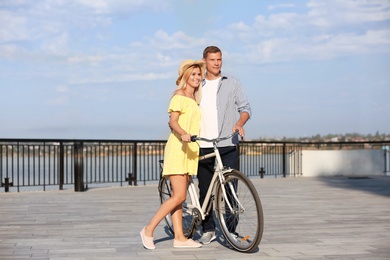 Happy couple with bicycle outdoors on sunny day