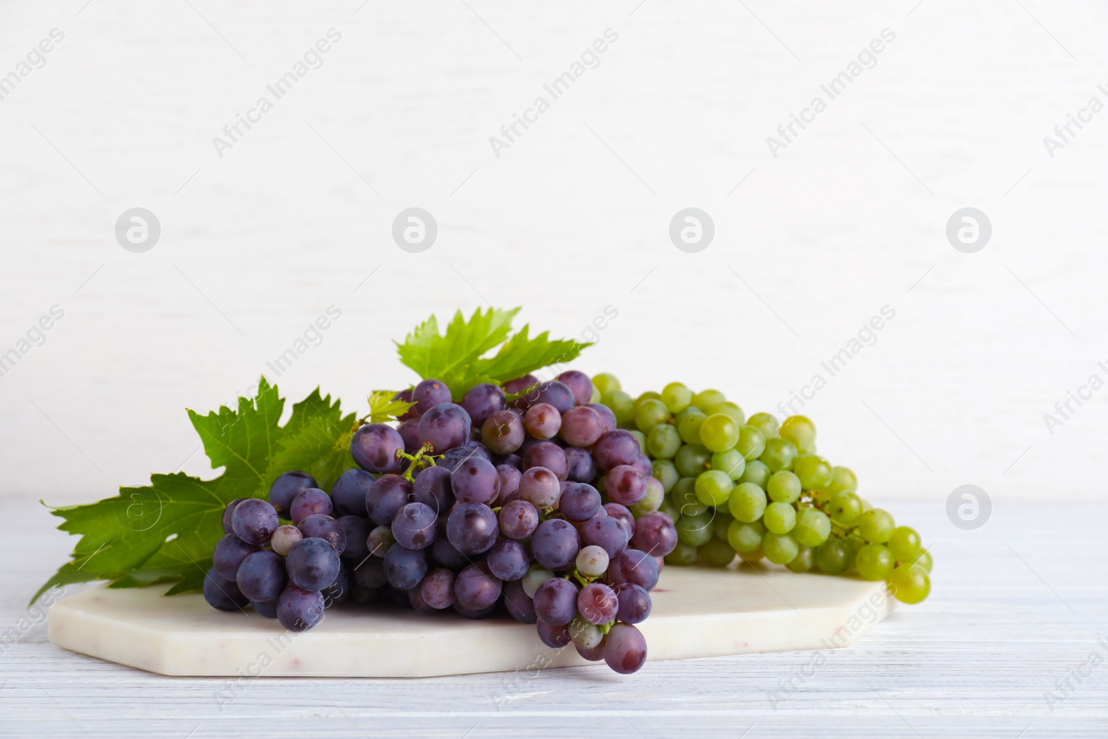 Photo of Fresh ripe juicy grapes on white wooden table