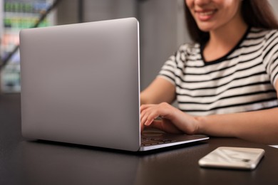 Photo of Young woman using laptop at table in hostel, closeup