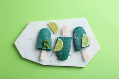 Photo of Flat lay composition with delicious spirulina popsicles, board and lime slices on color background