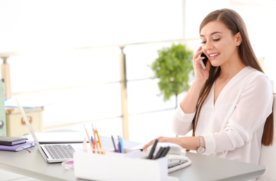 Young woman talking on phone at workplace