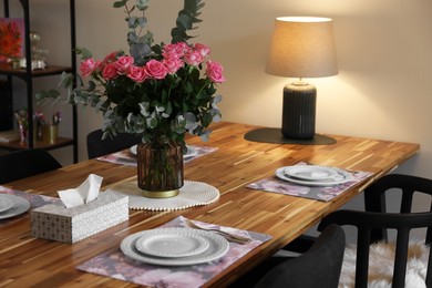 Beautiful table setting with bouquet and napkins indoors. Roses and eucalyptus branches in vase