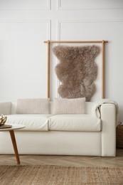 Photo of Comfortable sofa and hanging faux fur in modern room. Interior design