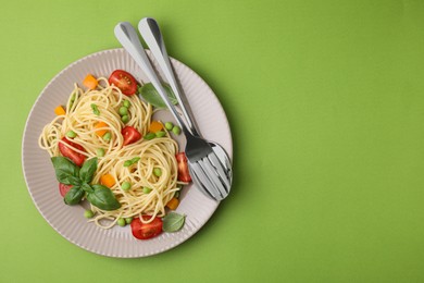 Photo of Plate of delicious pasta primavera and cutlery on light green background, top view. Space for text