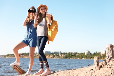 Teenage girls with binoculars on beach. Summer camp