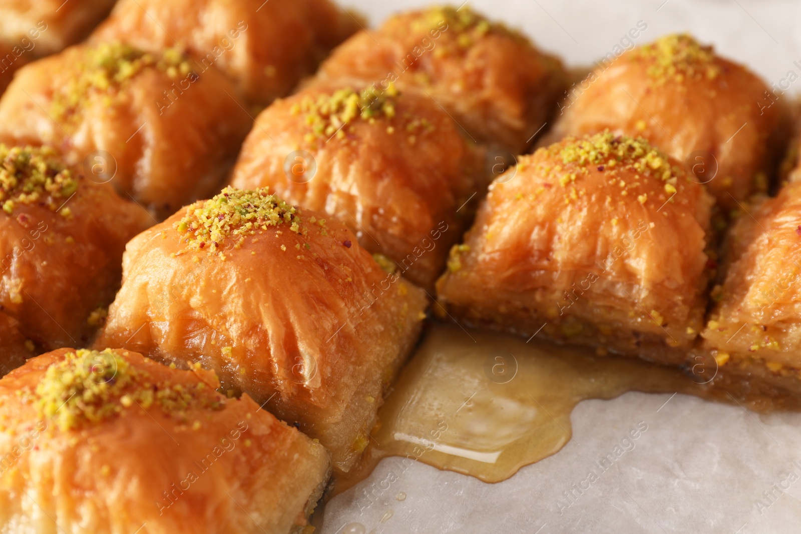Photo of Delicious sweet baklava with pistachios on parchment paper, closeup