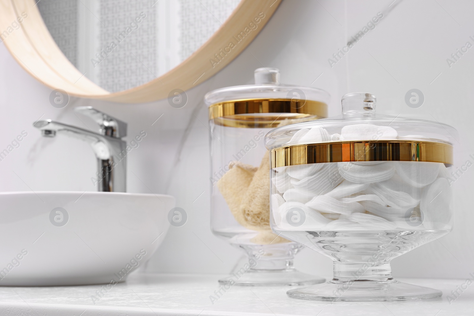 Photo of Glass jars with cotton pads and loofahs on table in bathroom. Space for text