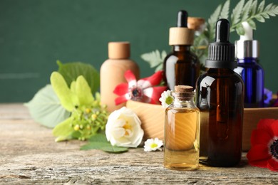 Photo of Aromatherapy. Different essential oils, flowers and green leaves on wooden table