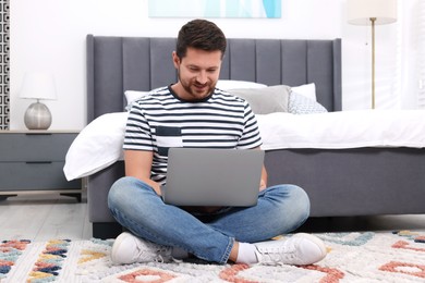 Photo of Happy man having video chat via laptop in bedroom