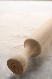 Photo of Rolling pin and flour on grey marble table, closeup