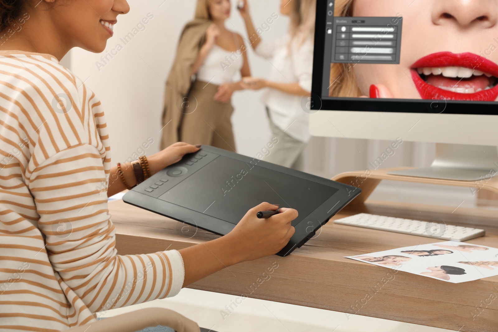 Photo of Professional retoucher working with graphic tablet at desk in photo studio, closeup