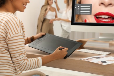 Photo of Professional retoucher working with graphic tablet at desk in photo studio, closeup