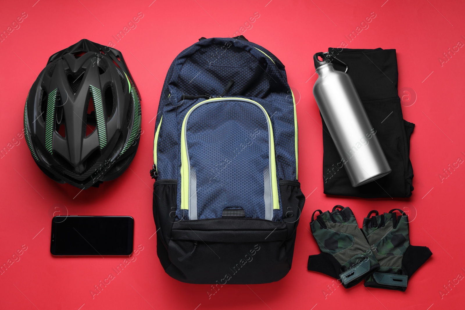 Photo of Flat lay composition with different cycling accessories and clothes on red background