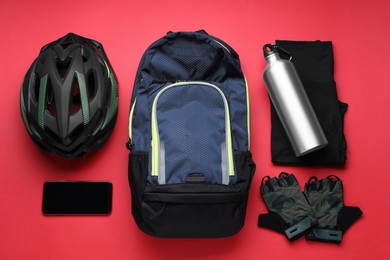 Photo of Flat lay composition with different cycling accessories and clothes on red background