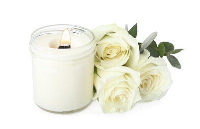 Photo of Aromatic candle with wooden wick and beautiful flowers on white background