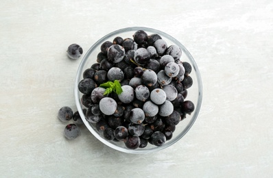 Tasty frozen black currants on white table, flat lay