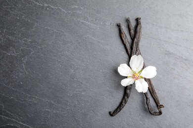 Flat lay composition with aromatic vanilla sticks and flower on grey background. Space for text