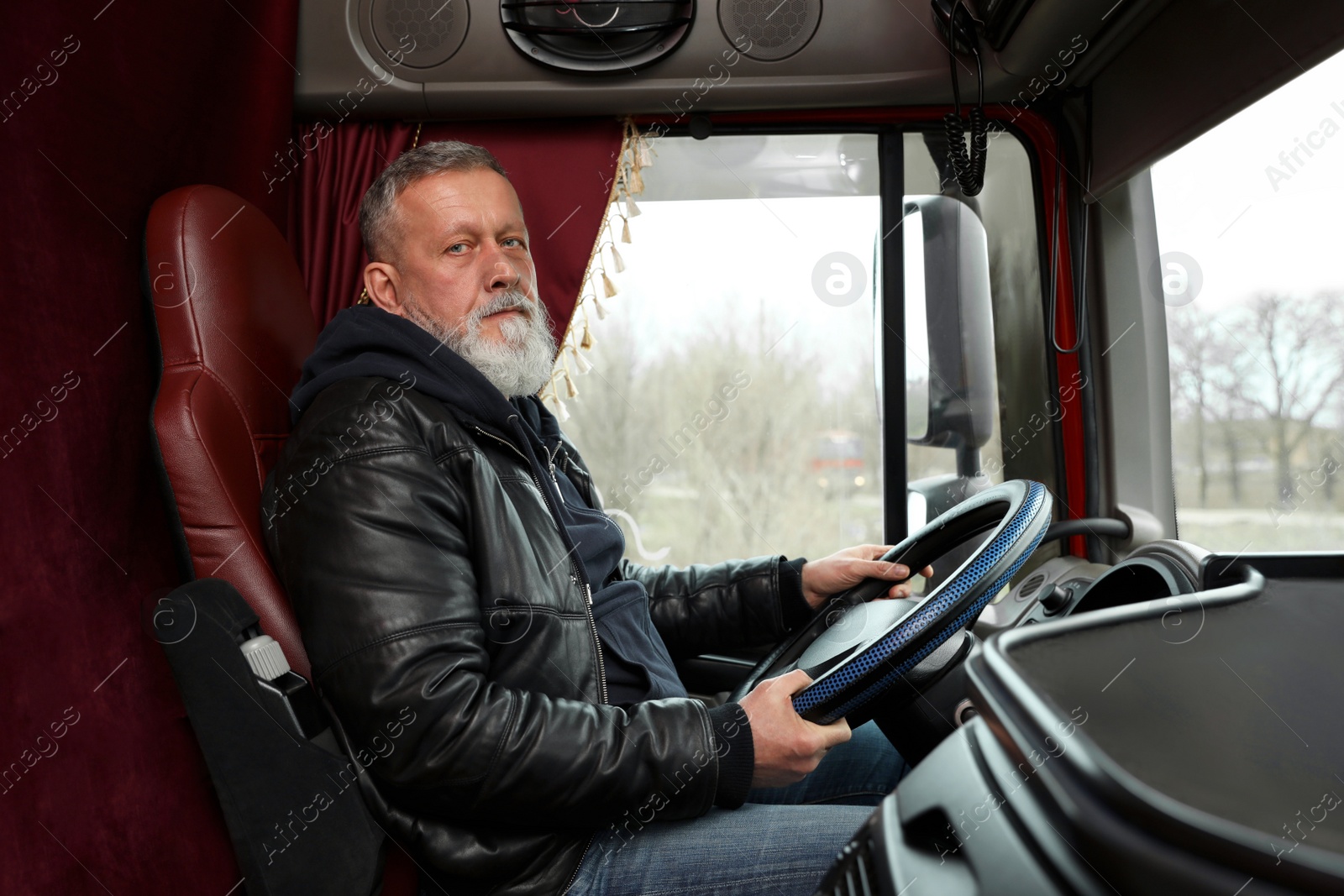 Photo of Mature driver sitting in cab of modern truck