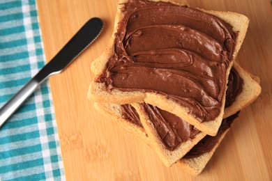 Photo of Tasty toasts with chocolate paste on wooden board, space for text