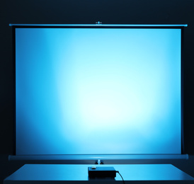 Photo of Video projector and screen indoors, toned in light blue. Space for design