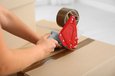 Woman packing carton box indoors, closeup. Moving day