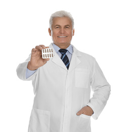 Senior pharmacist with pills on white background