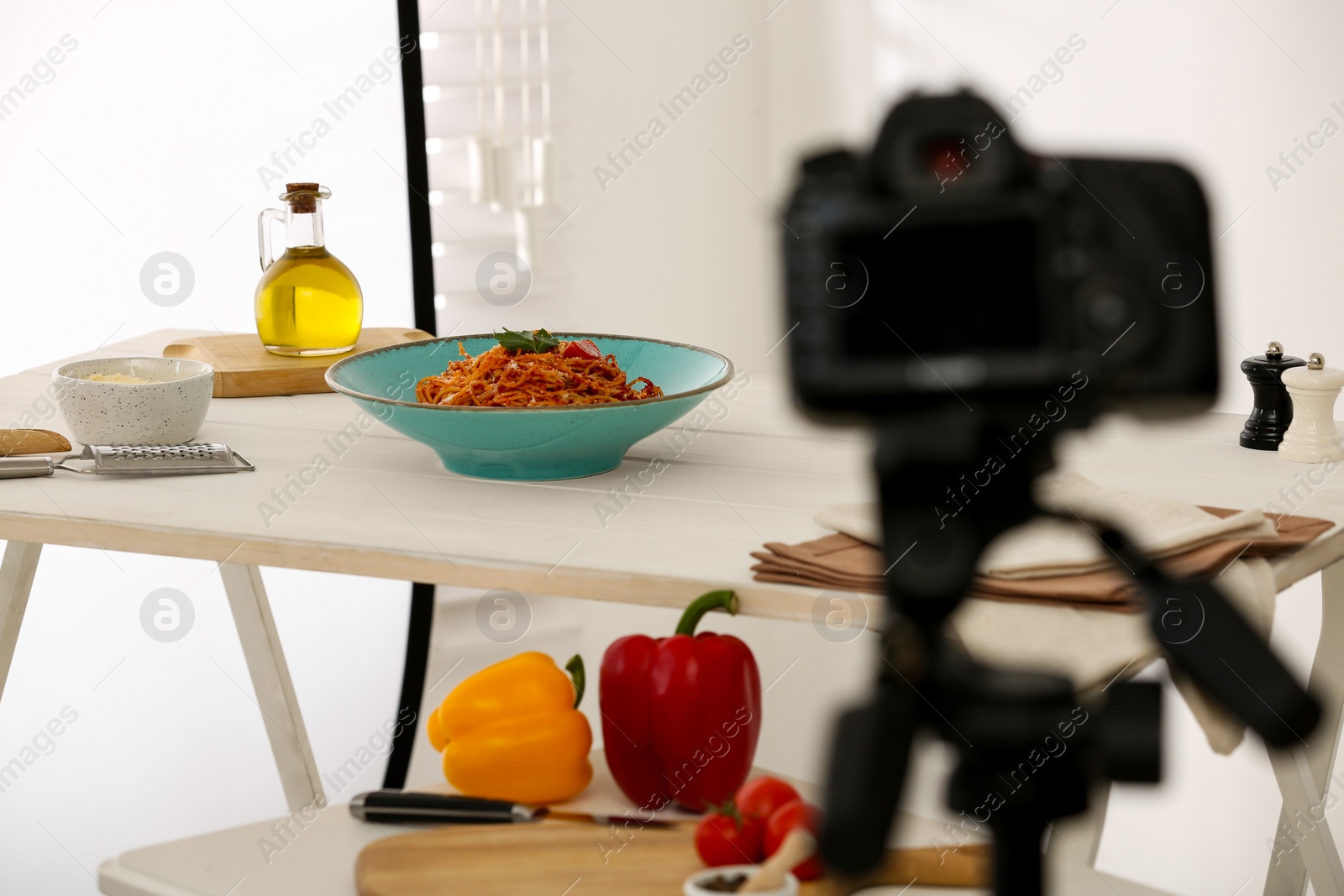 Photo of Professional camera and composition with spaghetti in photo studio, space for text. Food photography