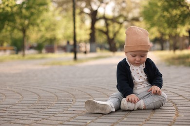 Portrait of little baby sitting in park. Space for text