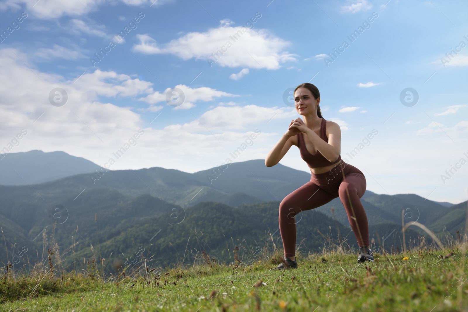 Photo of Young woman doing morning exercise in mountains, space for text