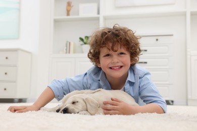 Little boy lying with cute puppies on white carpet at home